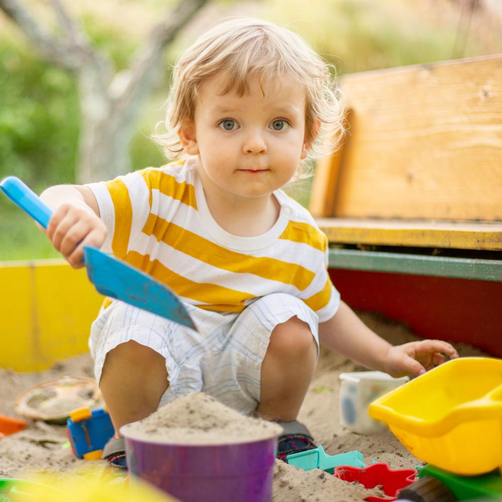 A toddler makes a sandcastle