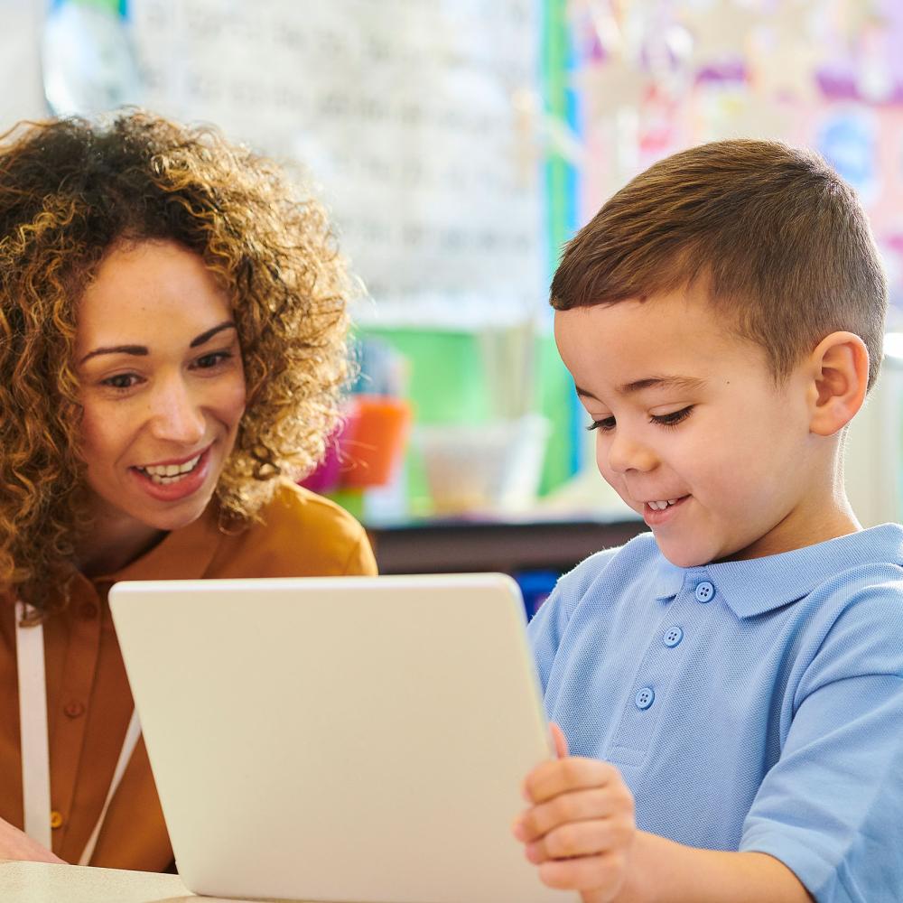 A woman and child smile and look at a tablet