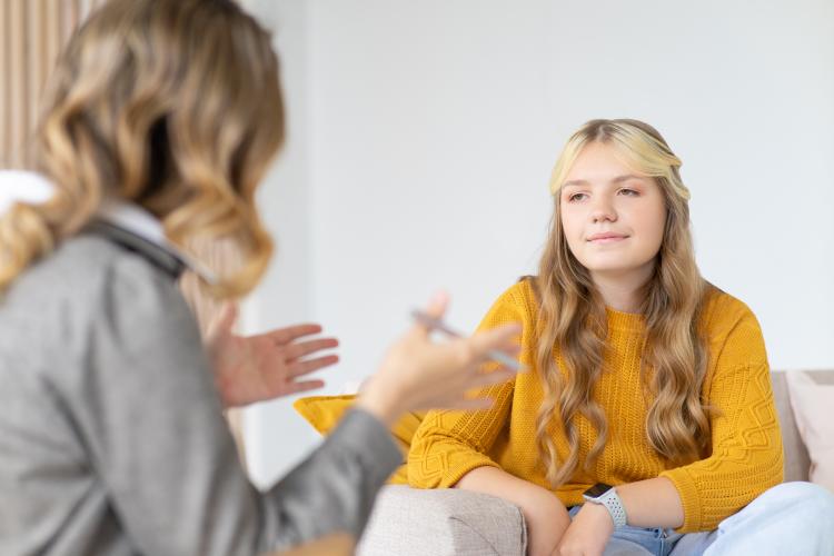 A girl provides feedback to a gesturing woman holding a pen