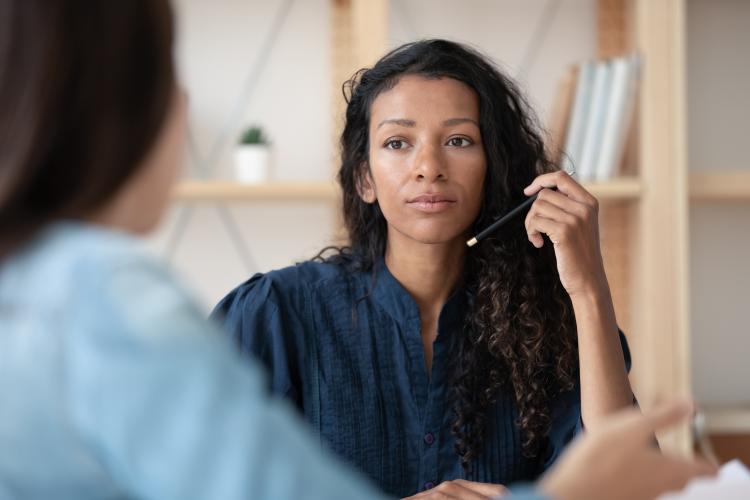 A woman talks with a recruitment colleague and holds a pen